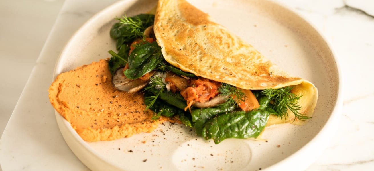 A close-up image of a golden brown omelette with herbs